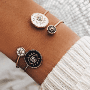A woman wearing a Black White Evil Eye Charm Cuff Bangle Bracelet with three charms on it.